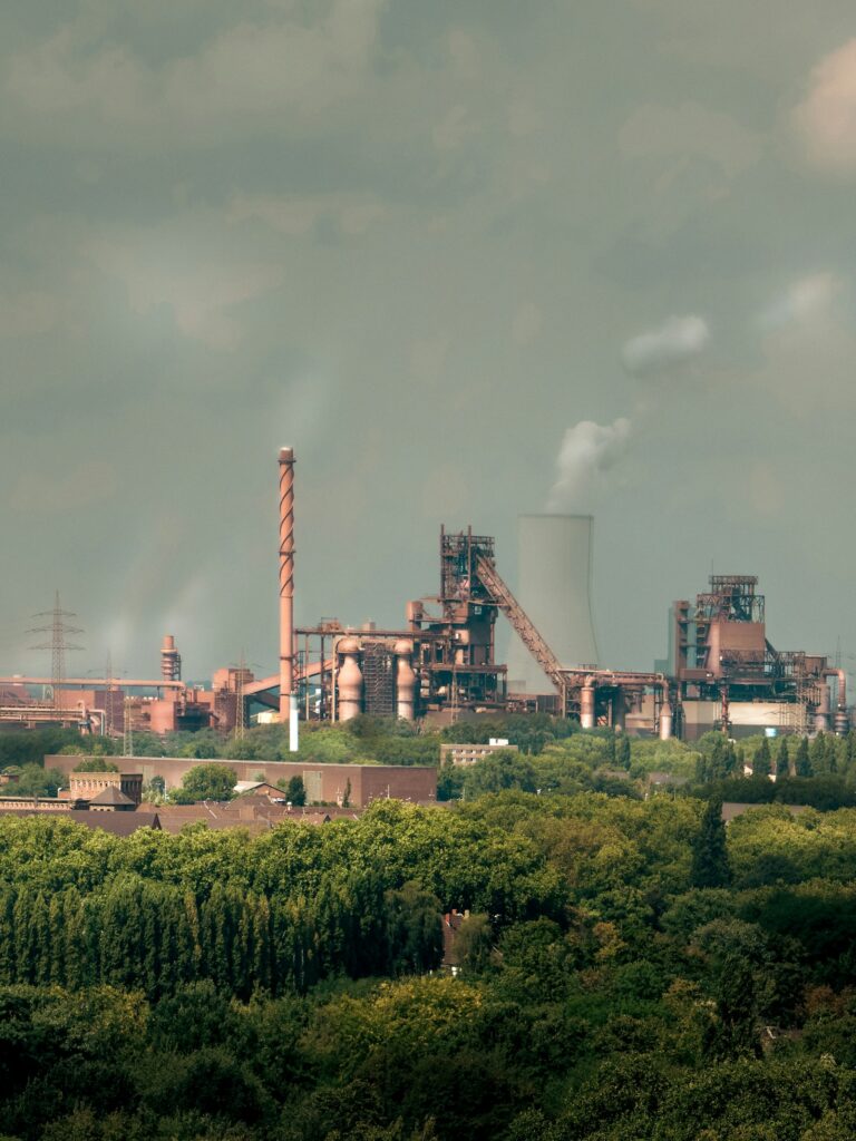 Climate Tech für die Industrie: Industrieanlage mit Schornsteinen in Duisburg, umgeben von Grün