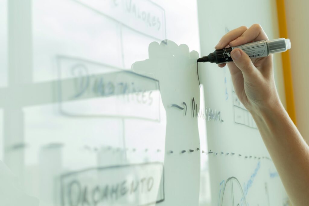 Low-Code im Mittelstand: Hand skizziert einen Prozess-Workflow als Diagramm auf einem Whiteboard