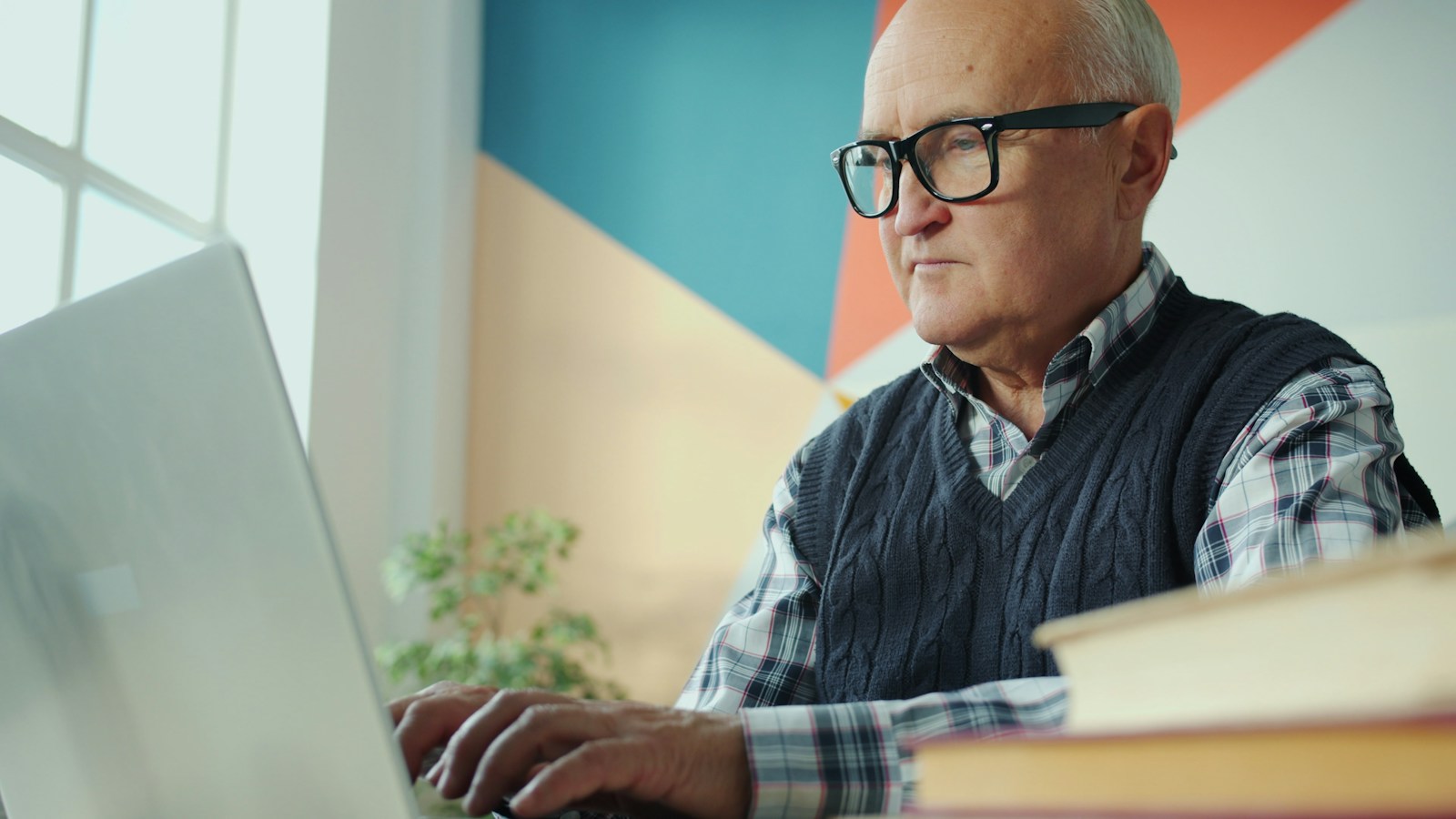 Aktivrente: Älterer Mann mit Brille arbeitet am Schreibtisch konzentriert an einem Laptop