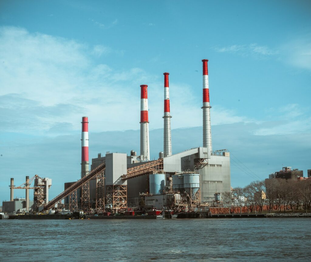 Deindustrialisierung: grau-rotes Industriegebäude am Wasser unter klarem blauem Himmel
