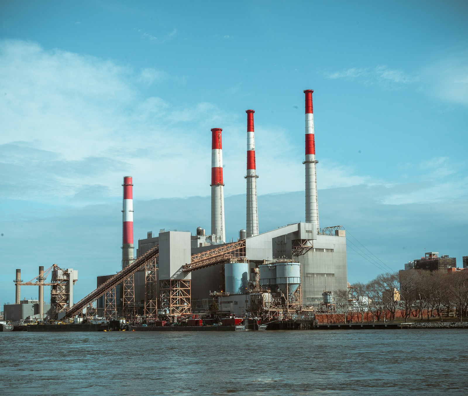 Deindustrialisierung: grau-rotes Industriegebäude am Wasser unter klarem blauem Himmel