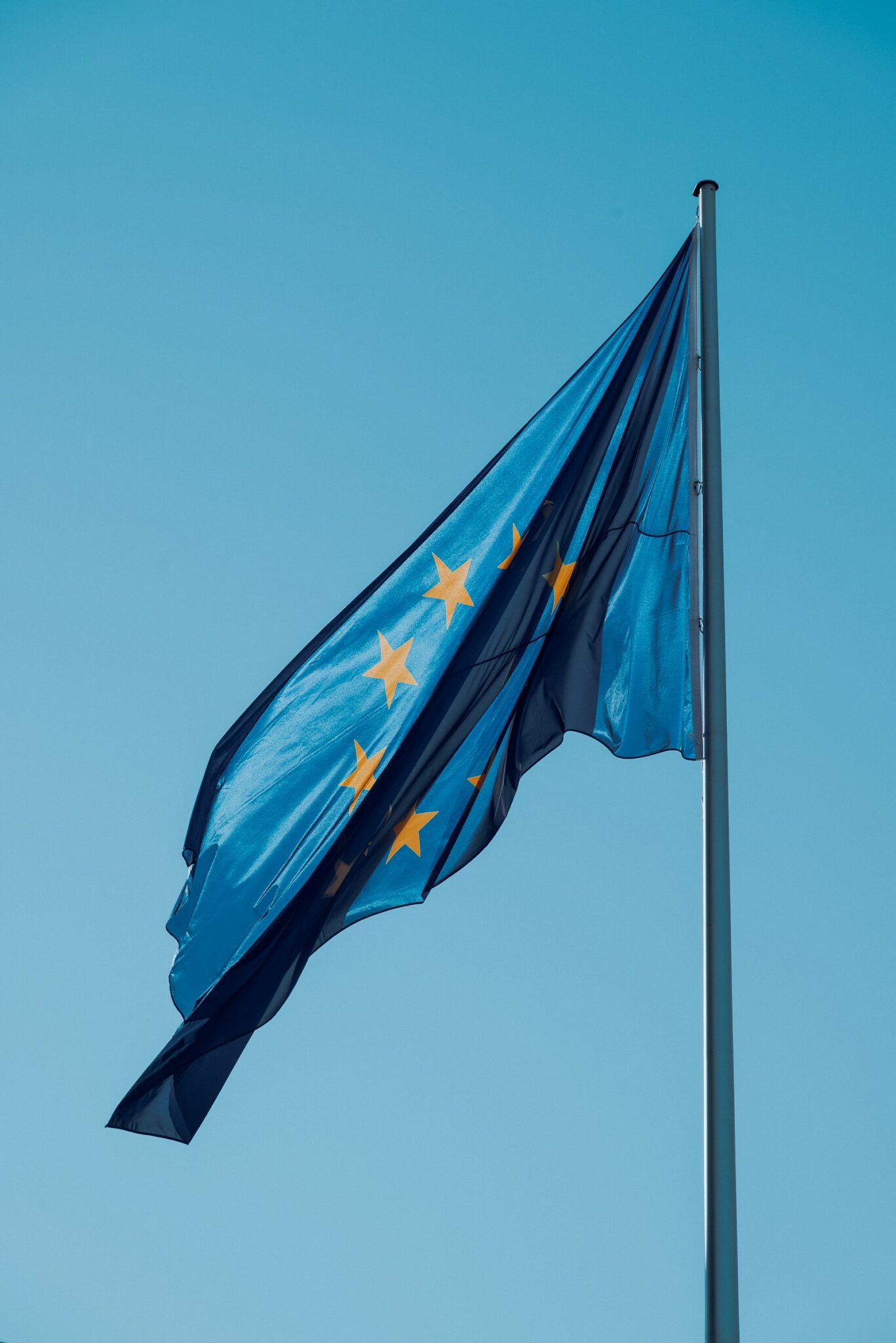 EU AI Act: Europaflagge mit gelben Sternen weht vor blauem Himmel