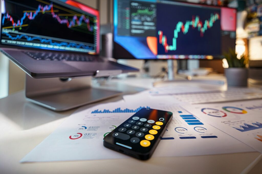 Liquiditätsplanung: Taschenrechner-App und Finanzcharts auf dem Schreibtisch