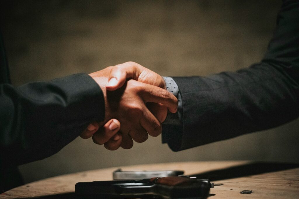 Unternehmensnachfolge: Zwei Personen geben sich über einem Holztisch die Hand