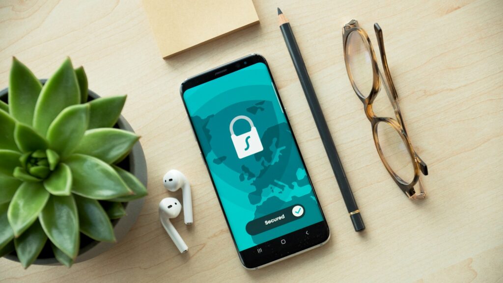 Passkeys auf dem Smartphone: Handy mit Schloss-Symbol auf einem Holzschreibtisch neben einer Sukkulente