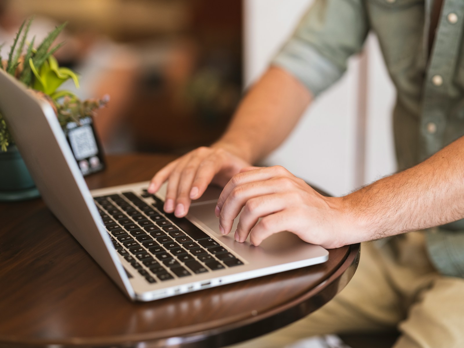 Verification of Payee: Mann tippt an einem Tisch auf seinem Laptop und gibt eine Überweisung ein